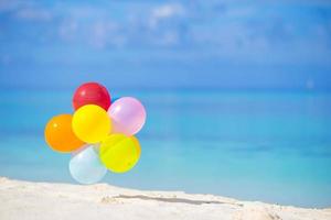 balões multicoloridos na praia tropical branca foto