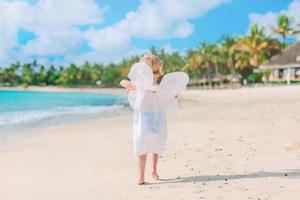 linda jovem vestindo asas de anjo na praia foto