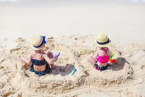 duas crianças fazendo castelo de areia e se divertindo na praia tropical foto