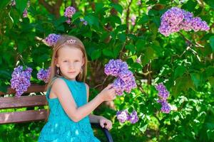 menina adorável no jardim de flores lilás florescendo foto