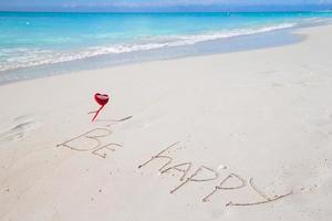 seja feliz escrito em uma praia tropical arenosa foto