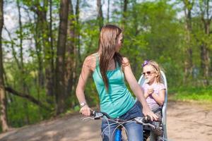 mãe feliz e filha andando de bicicleta no parque foto