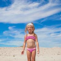 menina adorável em lindo maiô divirta-se na praia tropical foto