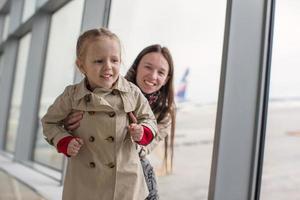 mãe e filha perto da janela no terminal do aeroporto foto