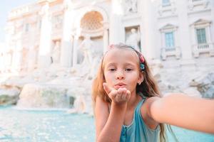 adorável menina tomando selfie na fonte de trevi em roma. foto