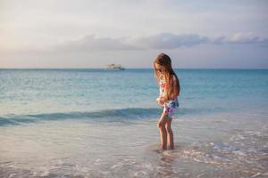 adorável menina andando na praia tropical branca foto