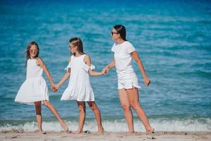 adoráveis meninas e jovem mãe na praia tropical branca foto