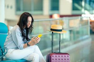 jovem mulher com café em um saguão de aeroporto esperando aeronaves de voo foto