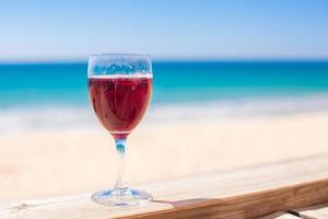 copo de vinho tinto fundo o mar turquesa foto