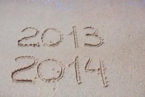2012 e 2013 escritos na areia da praia foto