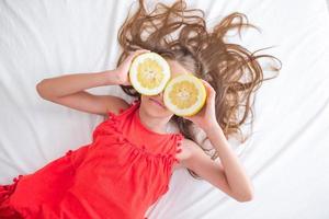 menina cobrindo os olhos com metades de limão perto dos olhos foto