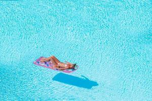 jovem em colchão de ar de biquíni na grande piscina foto