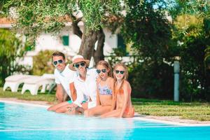 família de quatro pessoas feliz na piscina foto