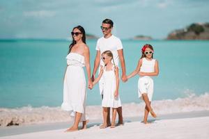feliz linda família de quatro pessoas na praia branca foto