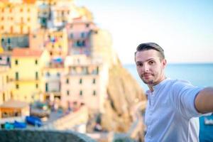 jovem tirando selfie fundo bela vila de manarola, cinque terre, ligúria, itália foto