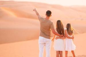 pessoas entre dunas no deserto nos Emirados Árabes Unidos foto