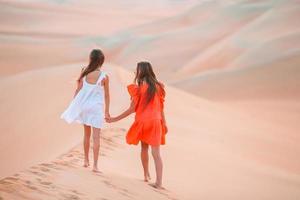 meninas entre dunas no deserto de rub al-khali nos Emirados Árabes Unidos foto