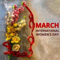 figura 8 feita de fita e flores artificiais para celebração do dia internacional da mulher em fundo prateado com espaço para texto foto