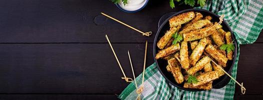 palitos de abobrinha assada com queijo e migalhas de pão. comida vegana. culinária vegetariana. bandeira. vista do topo foto