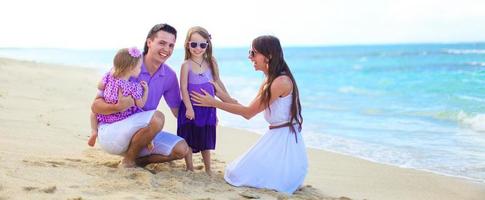 família feliz com dois filhos durante as férias na praia tropical foto