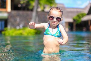 menina bonita e feliz na piscina durante as férias de verão foto