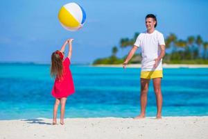 feliz pai e filha brincando com bola se divertindo ao ar livre na praia foto