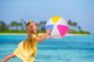 menina adorável brincando com bola de ar ao ar livre na praia foto