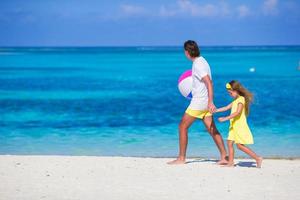 feliz pai e filha brincando com bola ao ar livre na praia foto