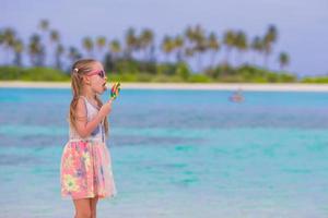 menina adorável com pirulito em férias de praia tropical foto