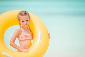 criança feliz com círculo de borracha inflável se divertindo na praia foto