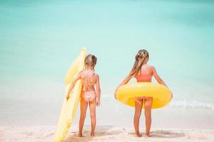 garotinhas engraçadas felizes se divertem muito na praia tropical brincando juntas. dia de sol com chuva no mar foto