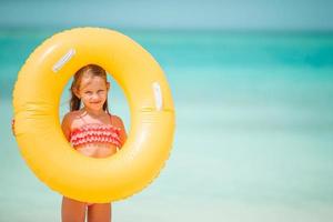 criança feliz com círculo de borracha inflável se divertindo na praia foto