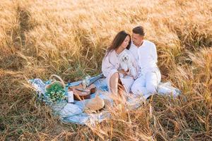 família jovem feliz no piquenique no campo de trigo amarelo foto