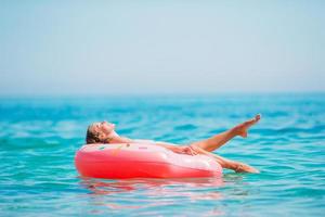 menina adorável no colchão de ar inflável no mar foto