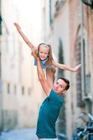 menina adorável e pai feliz durante as férias de verão italiano na rua estreita vazia foto