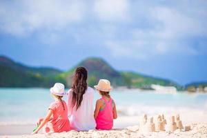 família de mãe e filhos com castelo de areia na praia tropical foto