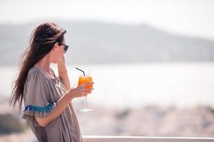 jovem mulher feliz no café ao ar livre com bebida saborosa. foto