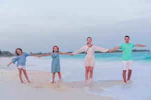 jovem família com dois filhos em férias na praia foto