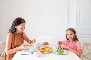 família feliz tomando café da manhã juntos na cozinha foto