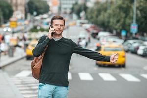 jovem homem caucasiano sorrindo feliz usando smartphone ao ar livre foto