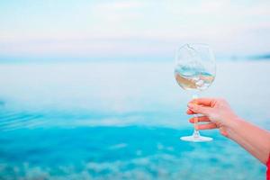 copo de vinho branco na praia tropical foto