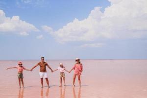 família caminha em um lago de sal rosa em um dia ensolarado de verão. foto