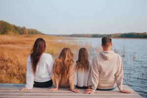 linda família no dia quente de outono perto do lago foto