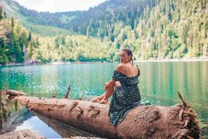 mulher romântica feliz sentada à beira do lago espirrando água foto