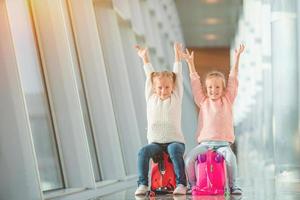 adoráveis meninas no aeroporto com sua bagagem à espera de embarque foto