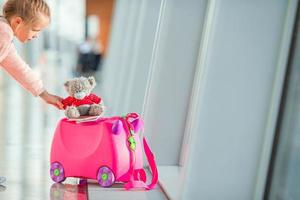 mala de crianças pequenas com urso de brinquedo no aeroporto internacional perto da janela foto