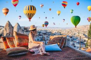 mulher jovem feliz durante o nascer do sol assistindo balões de ar quente na capadócia, turquia foto