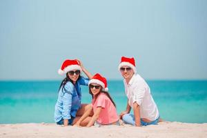 família feliz com dois filhos com chapéu de Papai Noel nas férias de verão foto