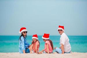 família feliz com dois filhos com chapéu de Papai Noel nas férias de verão foto