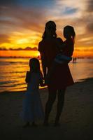 linda mãe e filha na praia apreciam a vista do pôr do sol foto